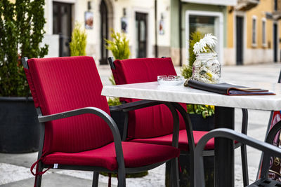 Empty chairs and tables at sidewalk cafe against building