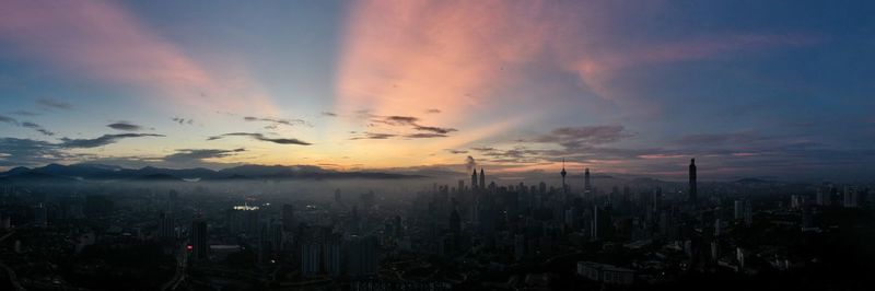 View of city against cloudy sky during sunset