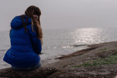 Rear view of woman at beach against sky