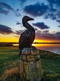 Statue on field against sky during sunset