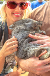 Woman with wombat sitting outdoors