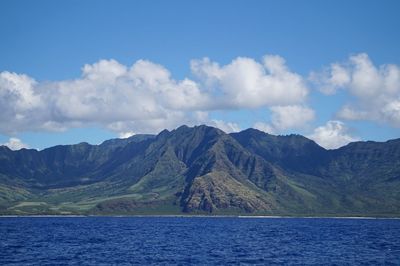 Scenic view of sea by mountains against sky