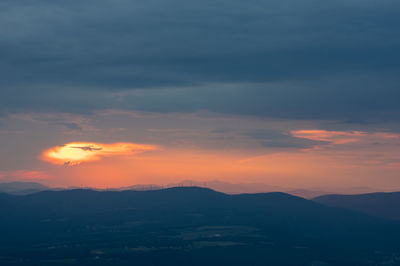 Scenic view of silhouette mountains against romantic sky at sunset