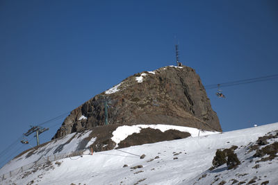 Low angle view of snowcapped mountain against clear blue sky