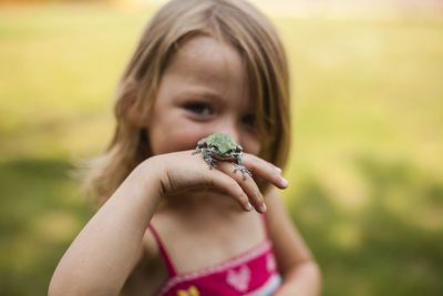Portrait of playful girl with frog standing in yard