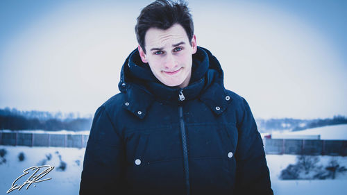 Portrait of smiling man wearing winter jacket against sky
