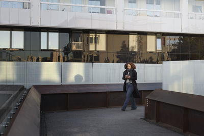 Beautiful woman with smartphone in front of office building