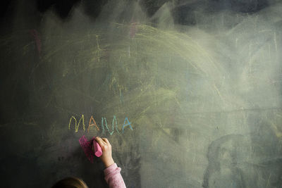 Cropped image of girl drawing on blackboard