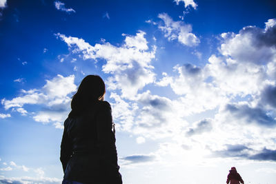 Low angle view of people against cloudy sky