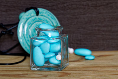 Close-up of blue medicines in jar on wooden table