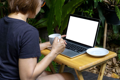 Midsection of man using mobile phone while sitting on table