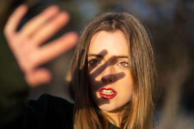 Close-up of beautiful woman shielding eyes during sunny day