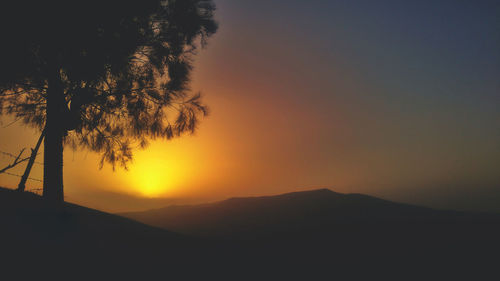 Scenic view of silhouette mountains against orange sky