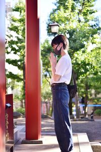 Full length of young woman standing against trees