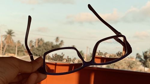 Close-up of hand holding glass against sky