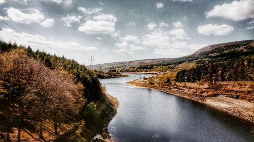 Scenic view of river by mountains against sky