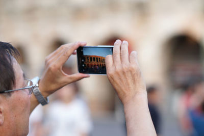 Midsection of man photographing with mobile phone