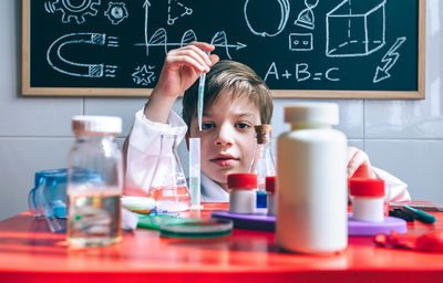 Portrait of boy doing scientific experiment on table in classroom