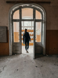 Rear view of woman standing at entrance of building abandoned