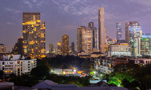 Illuminated buildings in city against sky at dusk