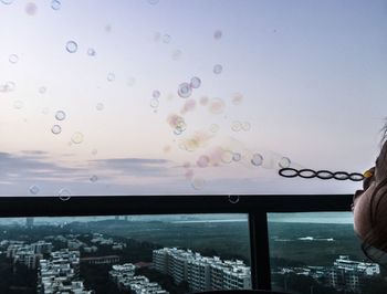 Child blowing bubbles on balcony in city