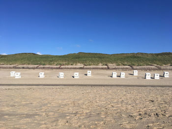 Hooded beach chairs against dunes and blue sky