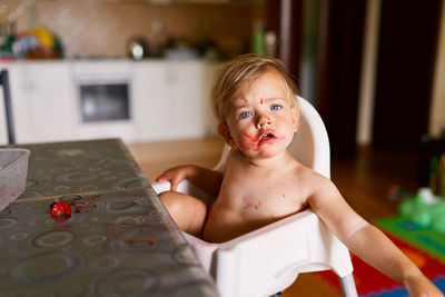 Portrait of shirtless boy looking at table at home