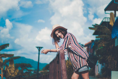 Woman standing by traditional windmill against sky