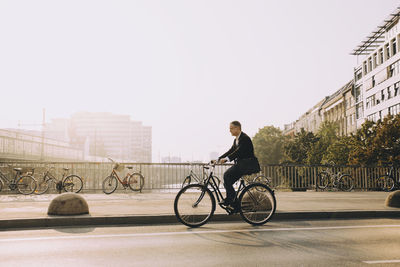 Man riding bicycle on city against sky