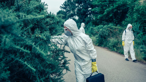Rear view of people walking against trees