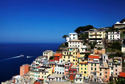 Townscape by ocean against clear blue sky
