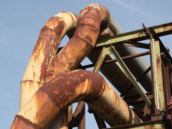 Low angle view of rusty pipe line against sky