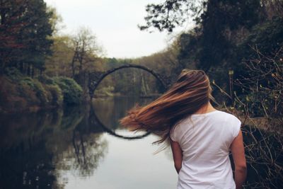 Rear view of woman standing by trees against sky