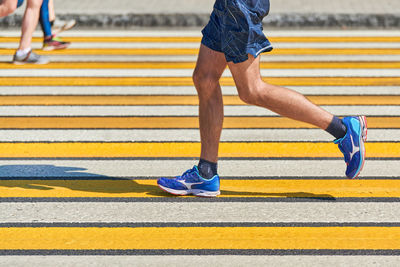 Man running crosswalk, copy space. athletic man jogging on city road. healthy lifestyle, fitness