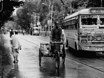 Rear view of people riding bicycle on road