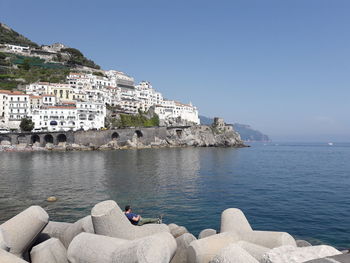 Buildings by sea against clear sky