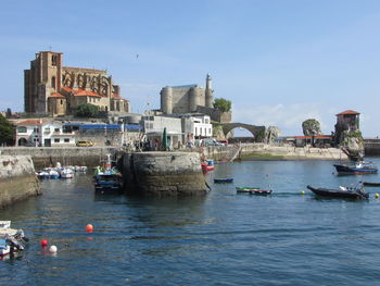 Boats in sea against buildings in city