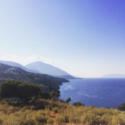 Scenic view of sea and mountains against clear blue sky