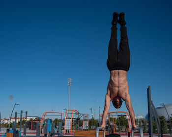 Low angle view of woman standing against clear blue sky