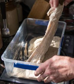 Cropped hands of woman kneading dough in container