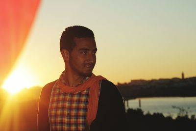 Young man looking away against sky during sunset