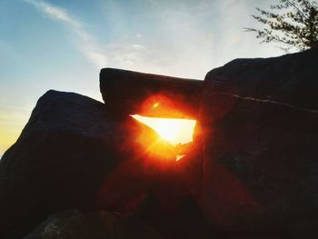Low angle view of sunlight streaming through rocks during sunset