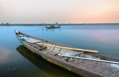 Boat moored in sea against sky during sunset