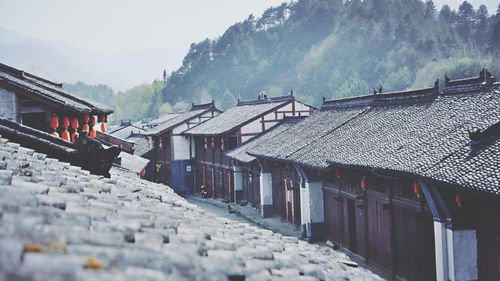 Houses on road amidst buildings against mountains during winter