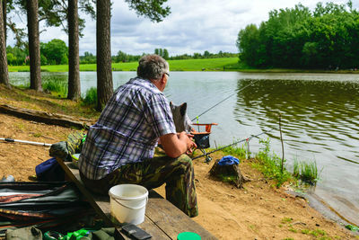 Sunny photo from summer with an angler, angler sits on the shore of the lake and catches fish