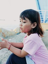 Side view of cute girl sitting outdoors