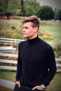 Young man looking away while standing outdoors