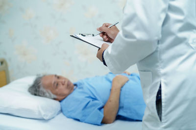 Midsection of doctor examining senior female patient at hospital