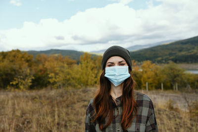 Portrait of young woman standing against sky