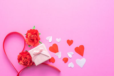 Close-up of heart shape with pink flowers over colored background